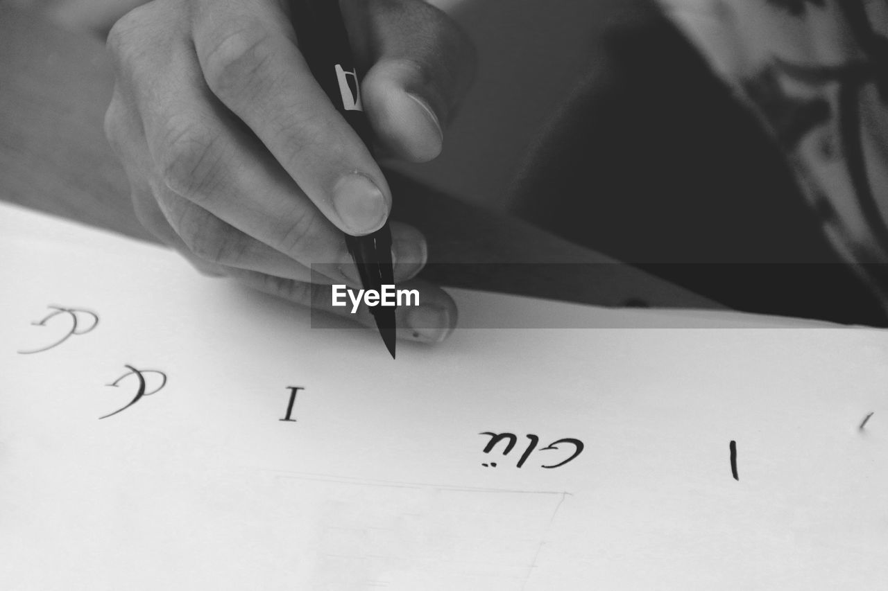 Cropped hand of person holding pen over paper