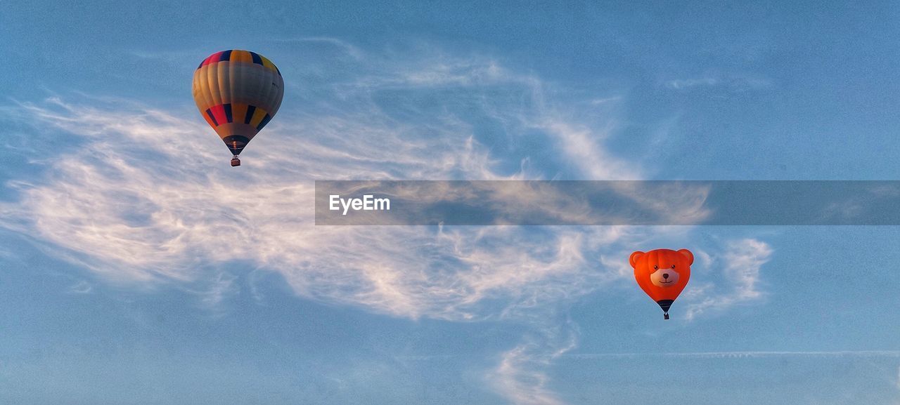 hot air balloon, air vehicle, balloon, flying, transportation, mid-air, hot air ballooning, vehicle, adventure, aircraft, sky, mode of transportation, toy, multi colored, nature, cloud, travel, blue, extreme sports, environment, motion, sports, leisure activity, ballooning festival, joy, low angle view, journey, day, outdoors, recreation, wind, basket, on the move, red, air sports, air travel, parachute, wing, trip, vacation, exhilaration, fun, holiday, outdoor pursuit, no people, taking off, beauty in nature, group of objects