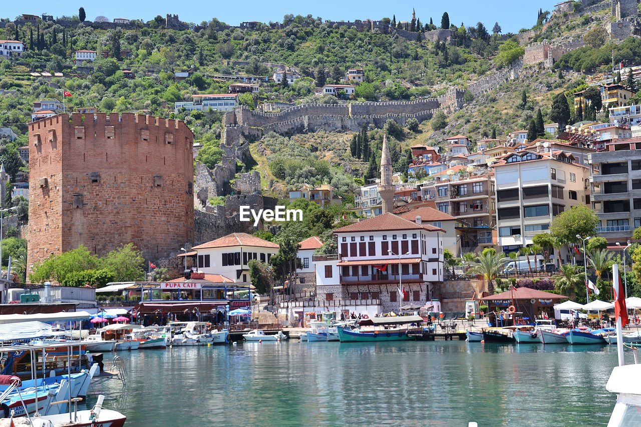 Sailboats moored on river by buildings in city