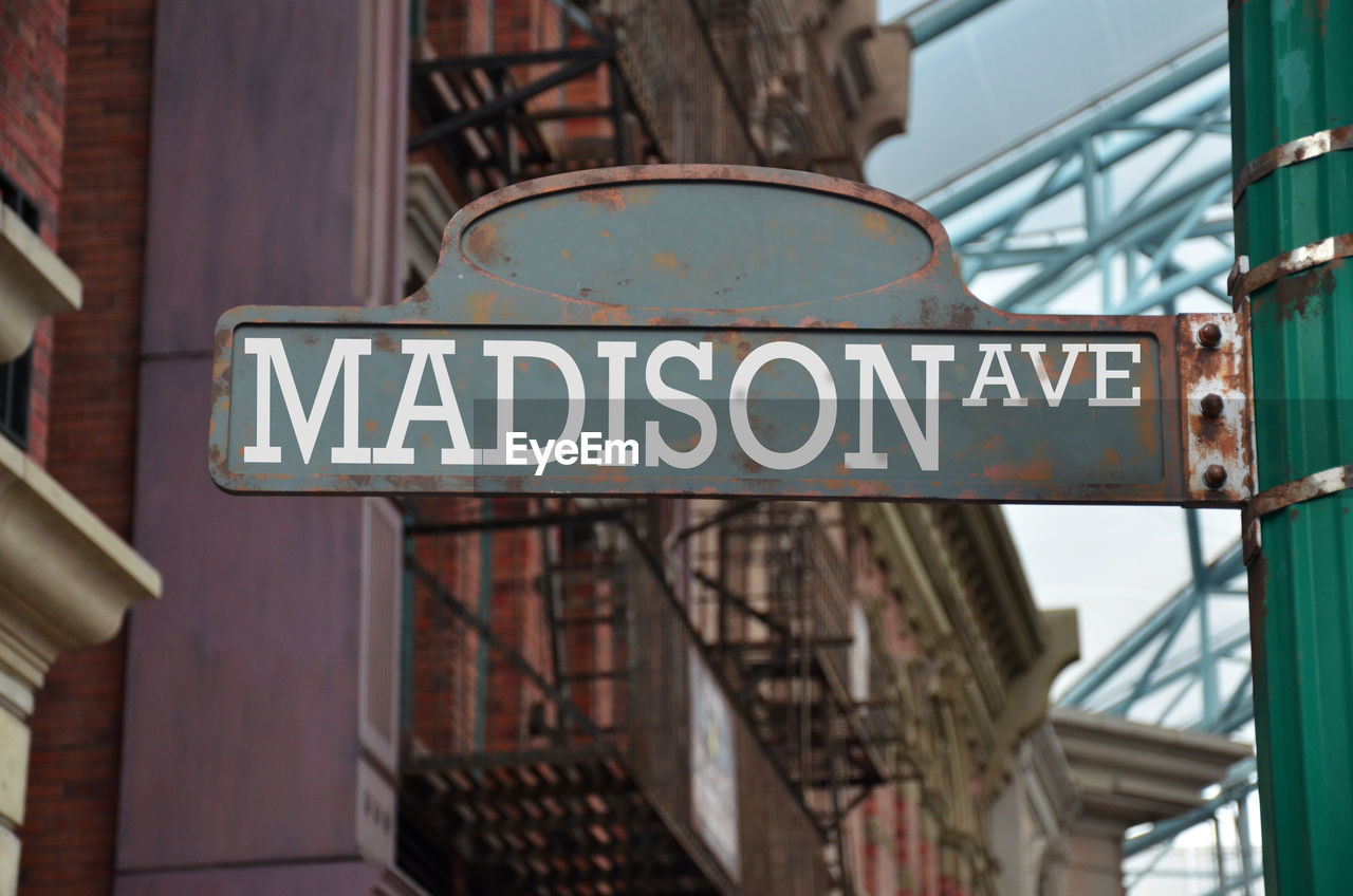 Low angle view of madison avenue sign against buildings in city