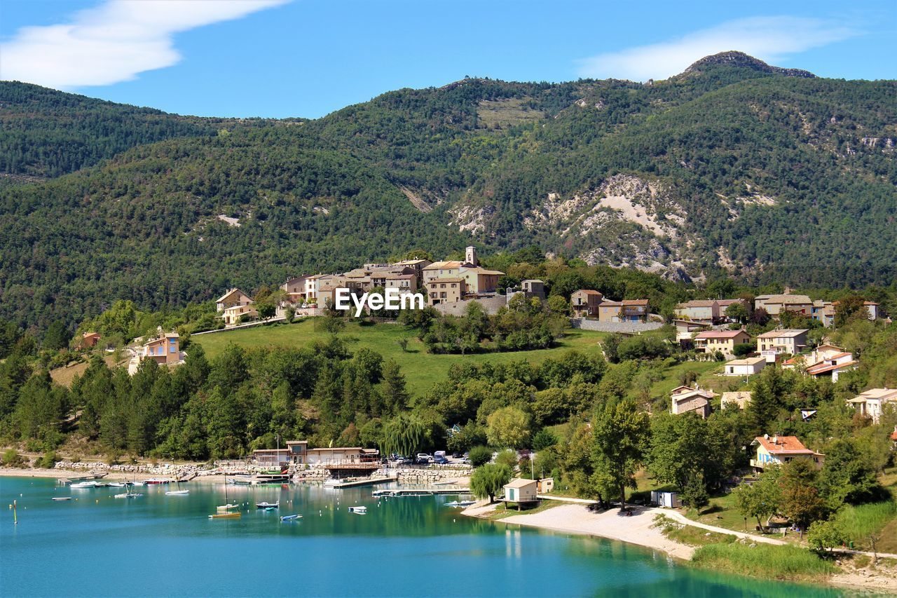 Scenic view of townscape by mountain against sky