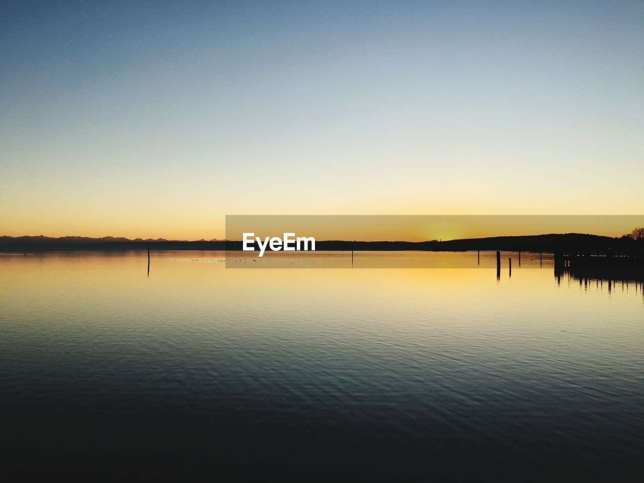 SCENIC VIEW OF LAKE AGAINST CLEAR SKY AT SUNSET