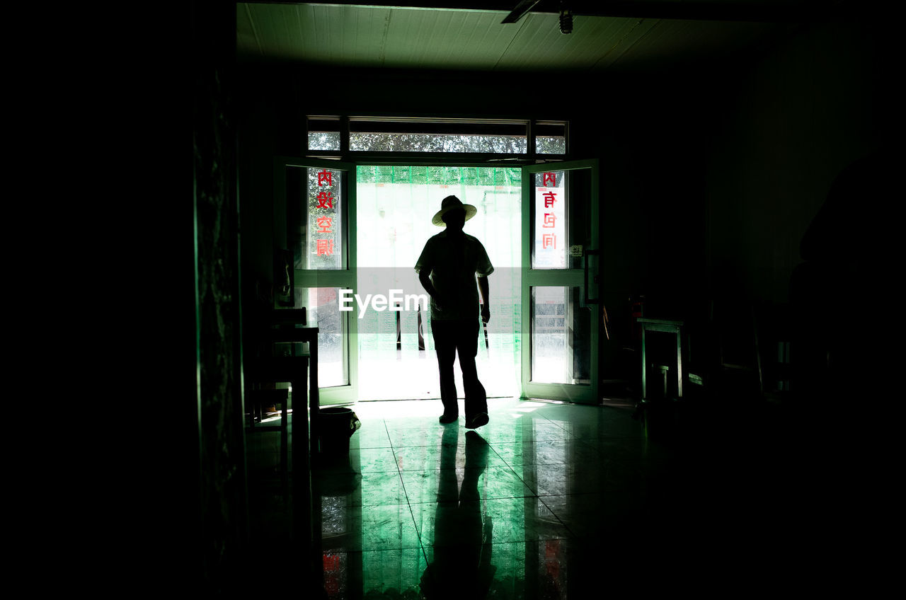 Silhouette man with hat walking in corridor