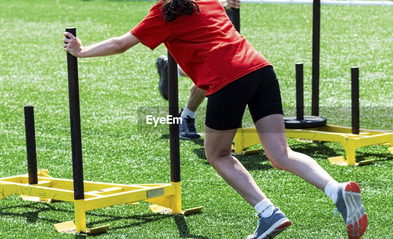 Low section of woman exercising with sled on turf ground