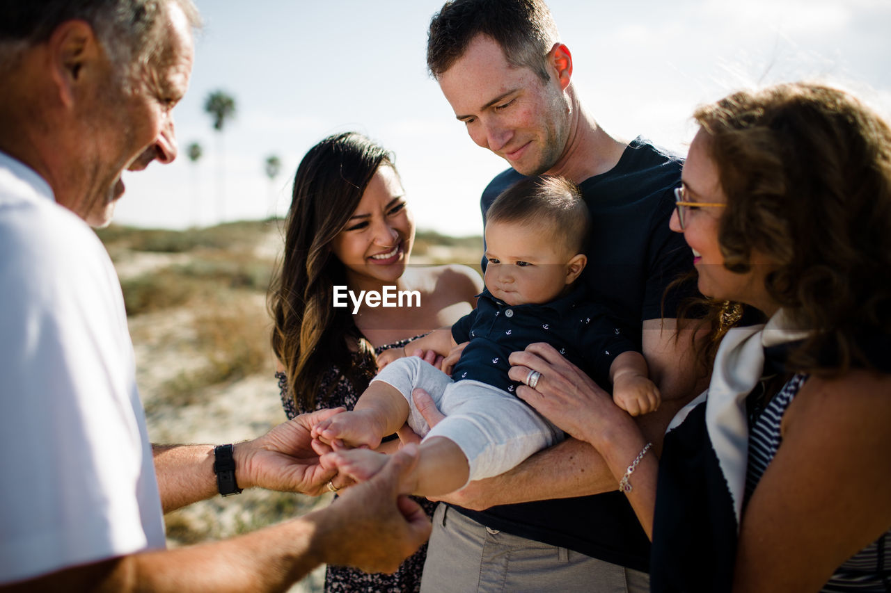 Family smiles as dad holds baby on beach