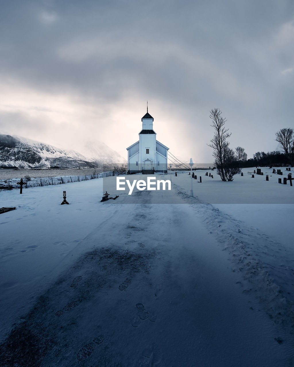 Snow covered cemetery against cloudy sky