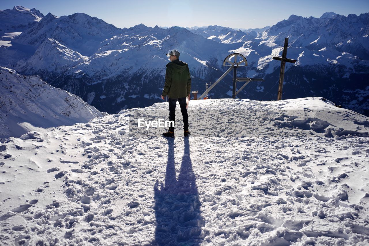 Rear view of man standing on snowcapped mountain