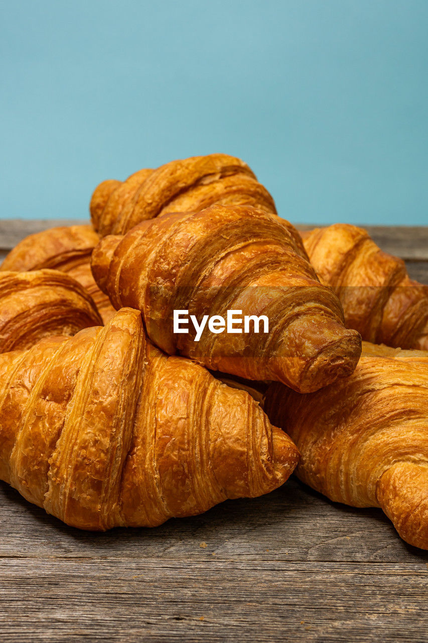 croissant, food and drink, food, baked, french food, freshness, no people, viennoiserie, dessert, still life, produce, table, bread, brown, fast food, close-up, indoors, studio shot, colored background, loaf of bread
