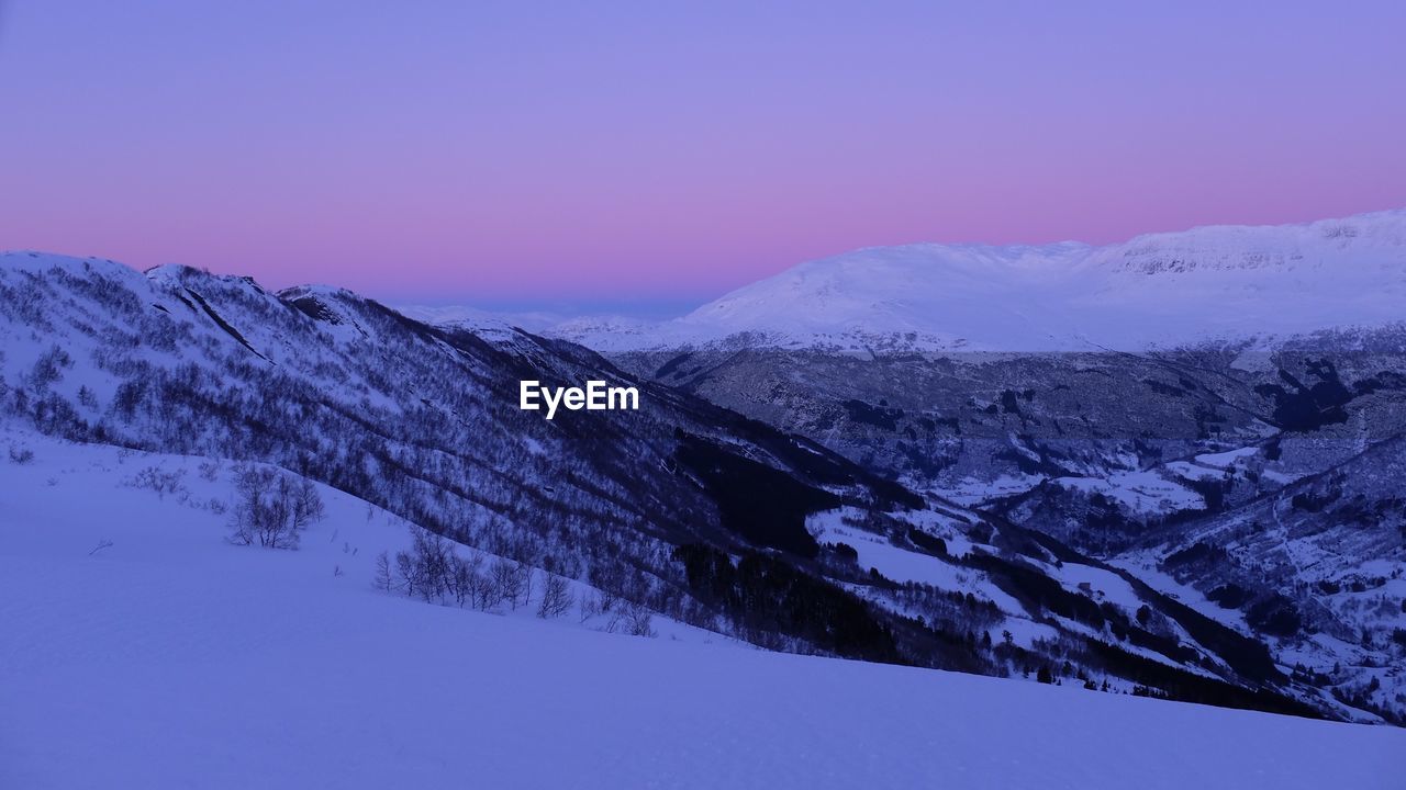 Scenic view of snow covered mountain against blue sky