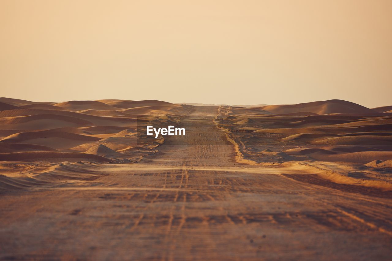 Empty desert road in the middle sand dunes. abu dhabi, united arab emirates