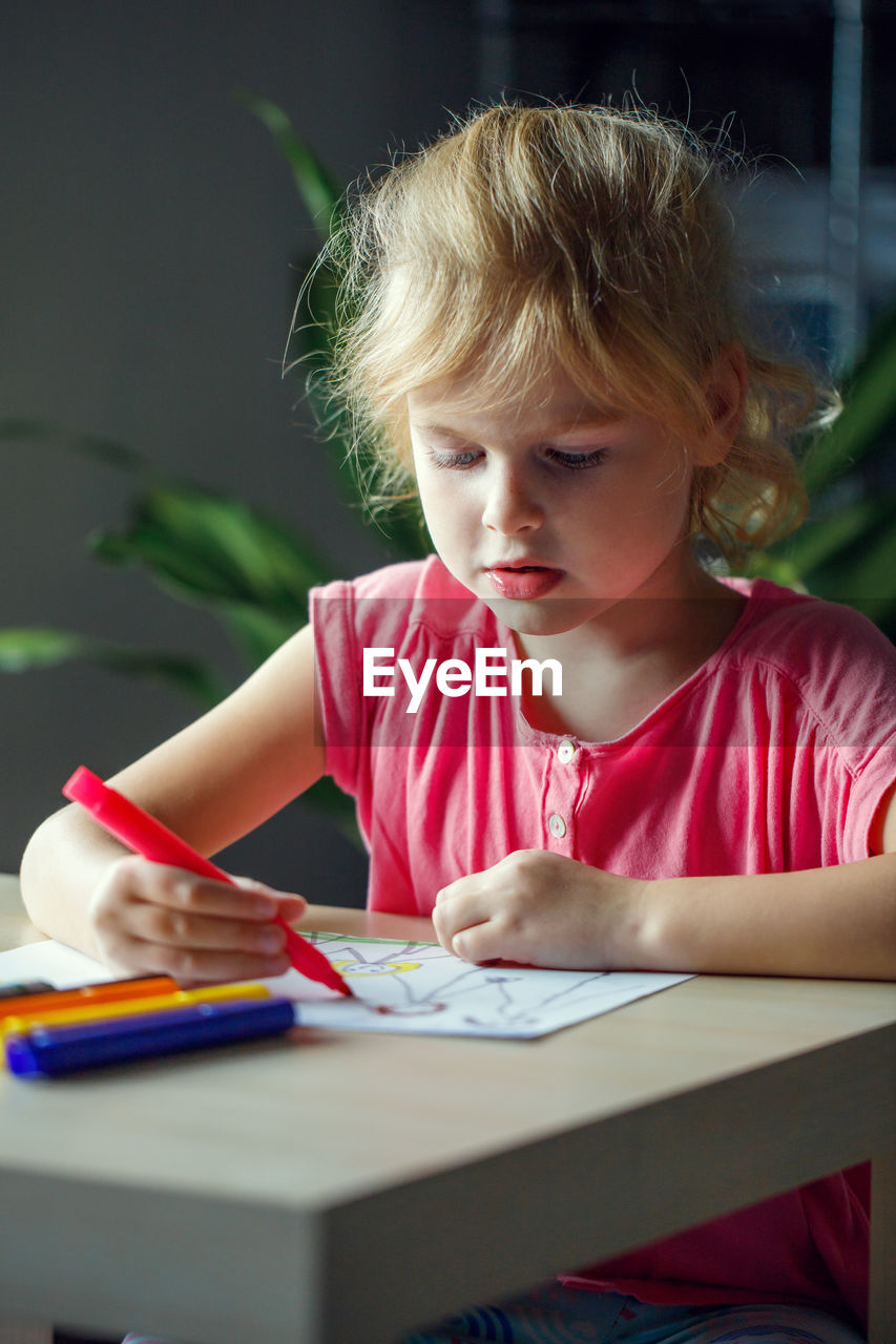 portrait of girl drawing on book at home