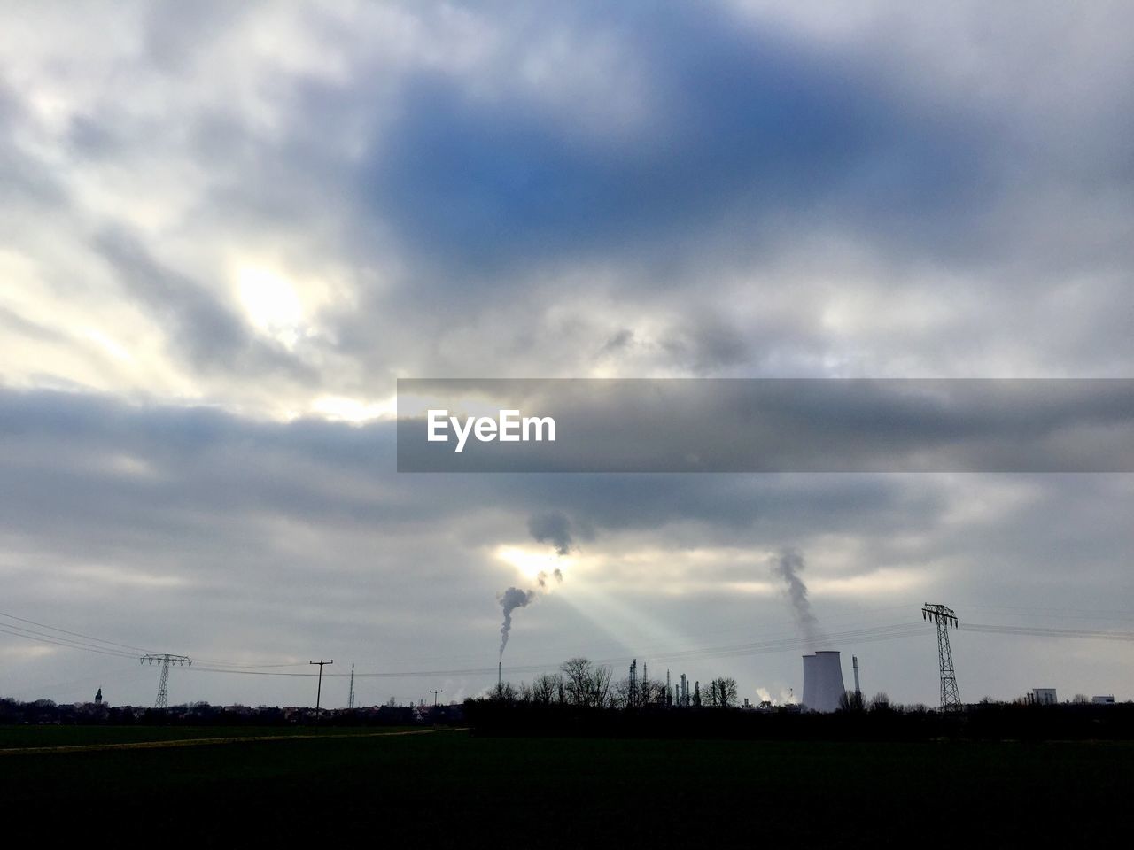 ELECTRICITY PYLONS ON FIELD AGAINST SKY