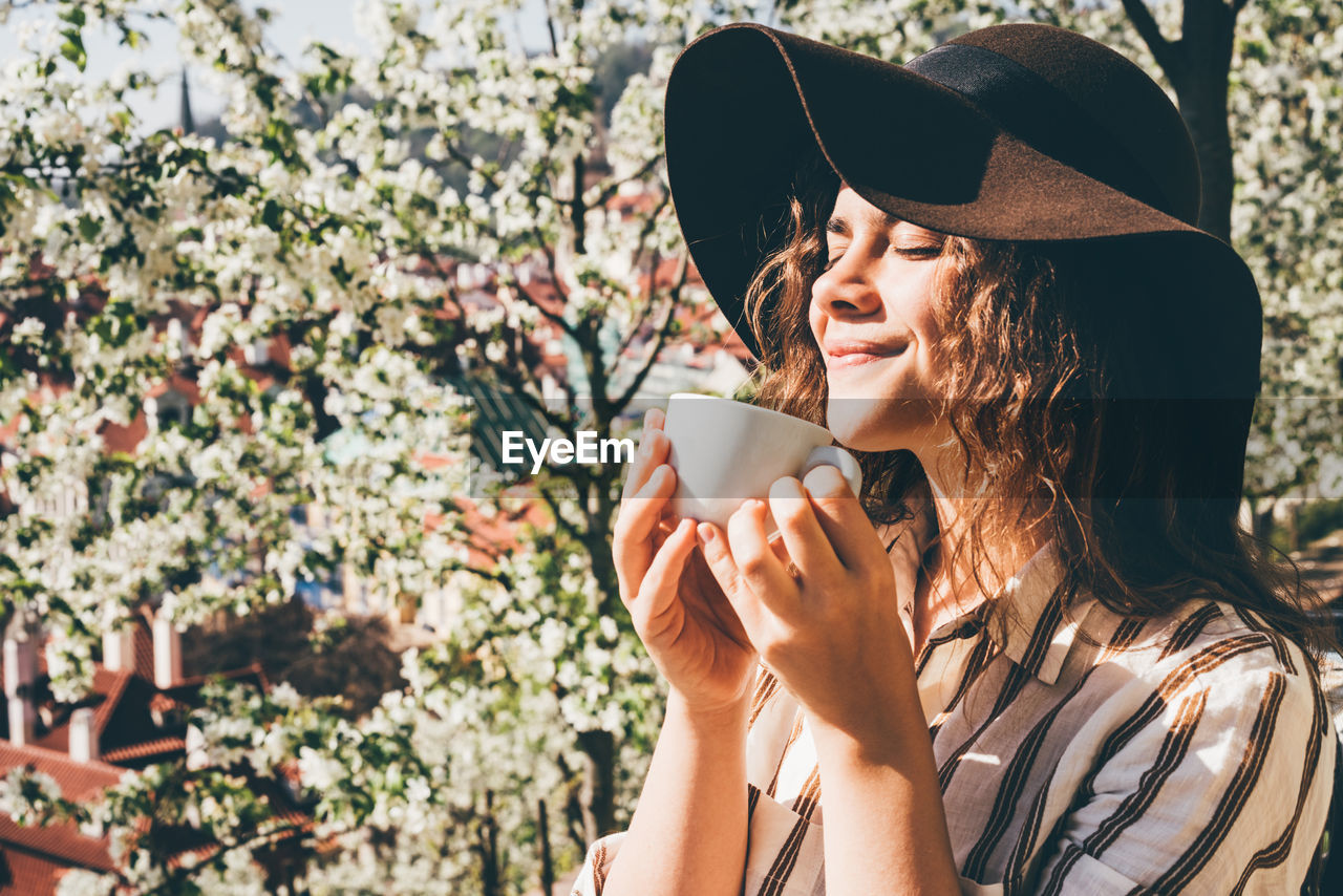 LOW ANGLE VIEW OF YOUNG WOMAN WITH COFFEE CUP