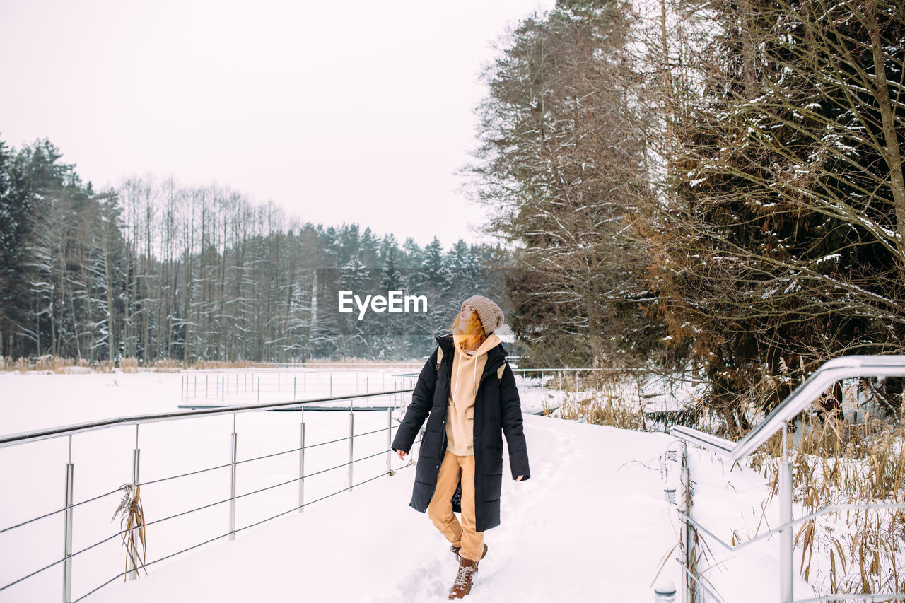 rear view of woman walking on snow covered field