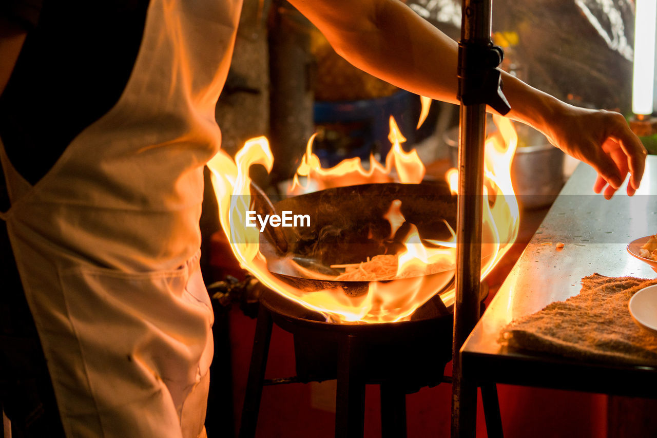 Midsection of chef preparing food in commercial kitchen