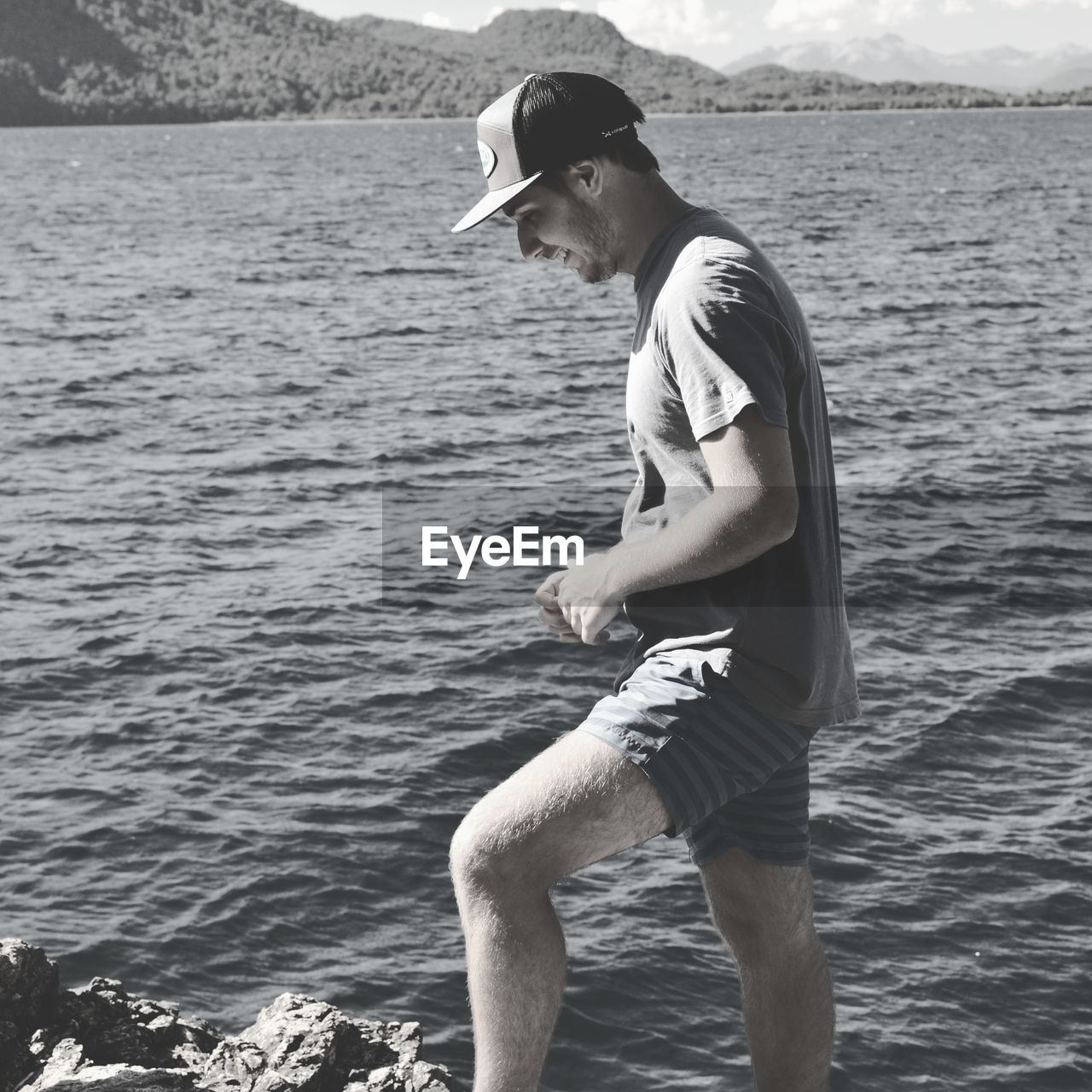 Side view of young man standing on rock by sea