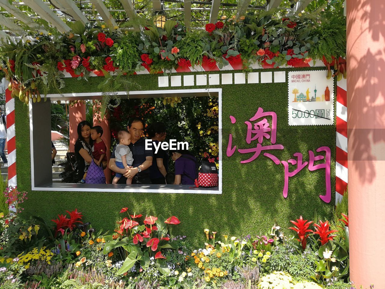 PEOPLE IN FRONT OF RED FLOWERS