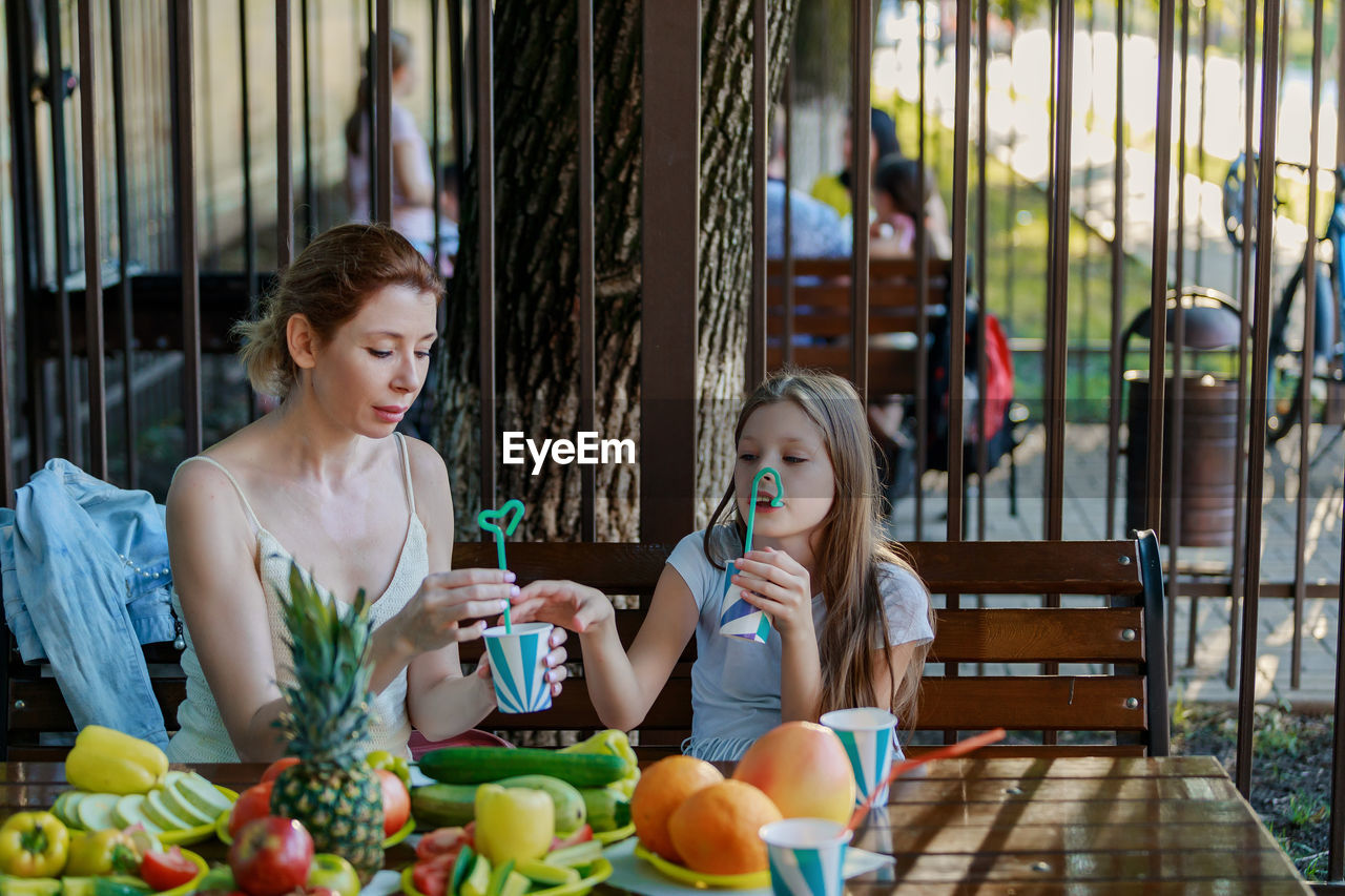 Mother and daughter drinking juice while sitting at restaurant