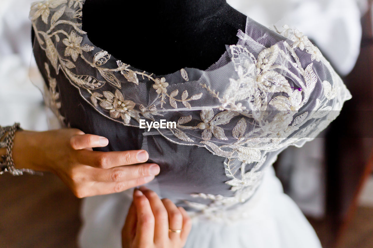 Cropped image of fashion designer adjusting wedding dress on mannequin