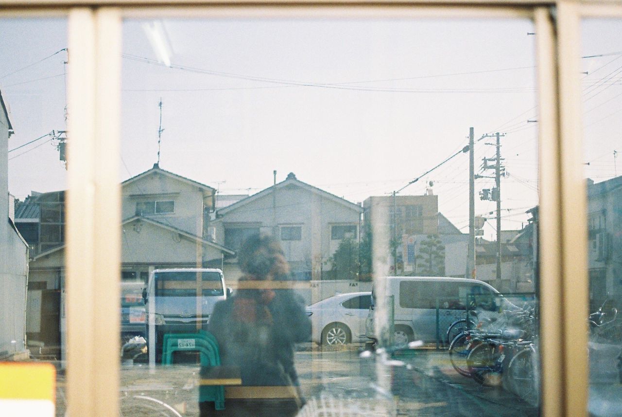 Woman taking selfie on window glass reflection