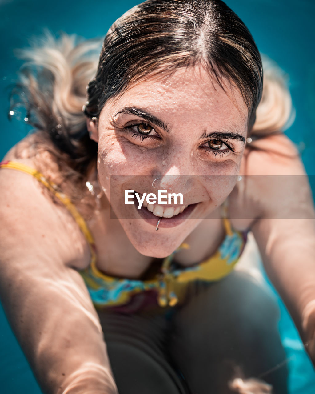 Content young female in swimwear in warm pool water on sunny day