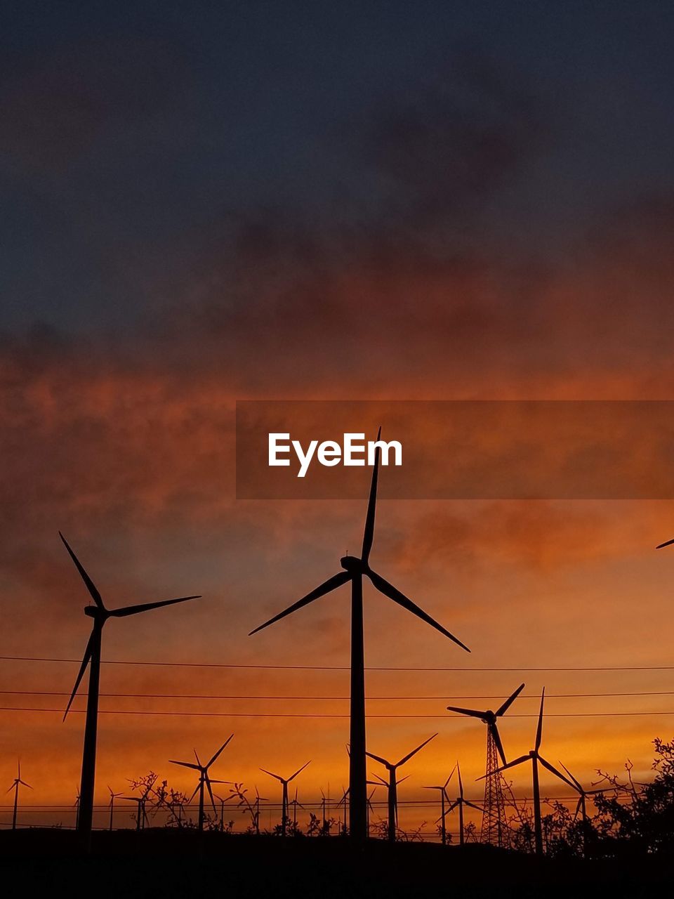 Low angle view of electricity pylon against sky during sunset