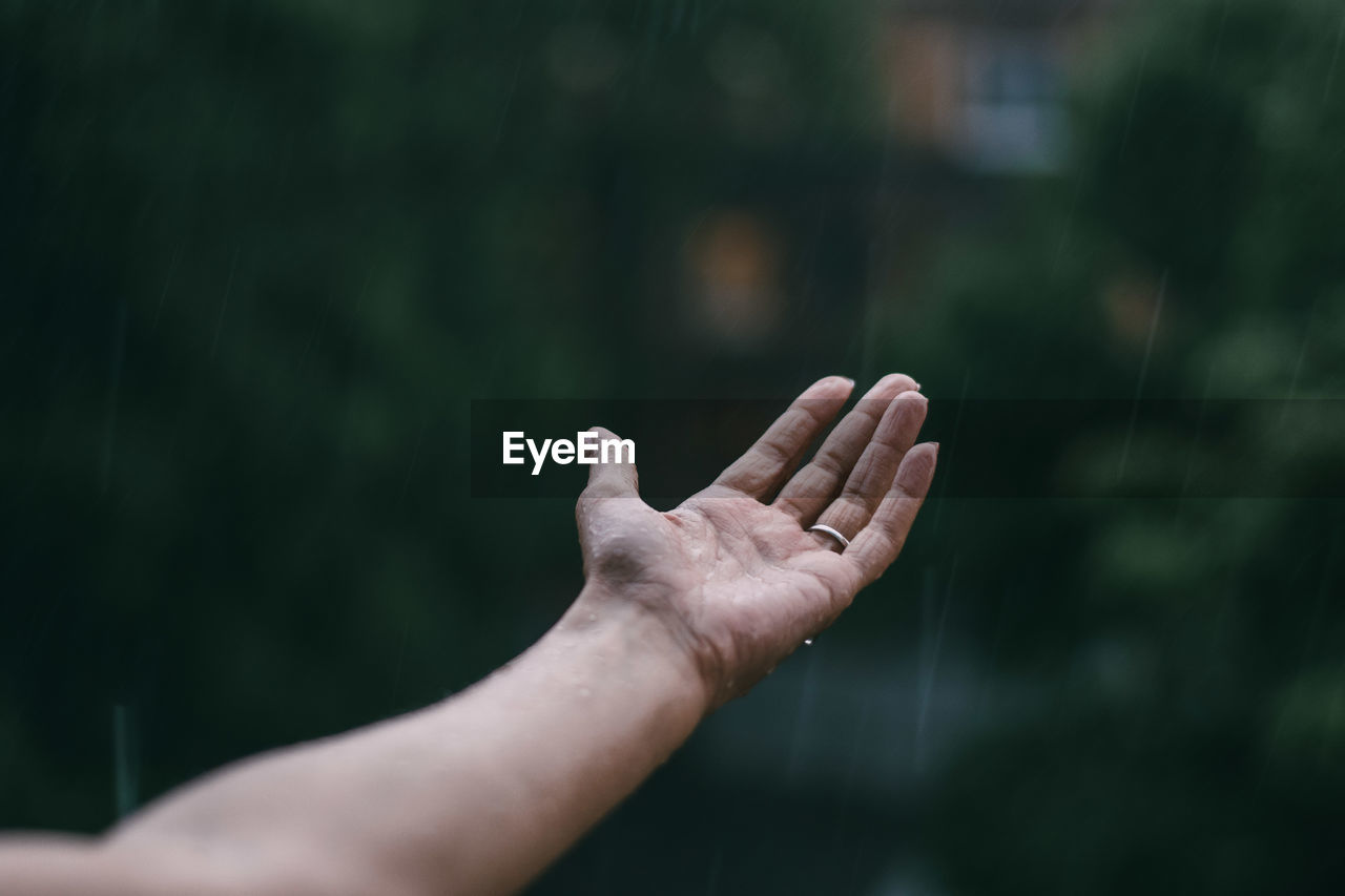 Cropped hand of woman feeling rain