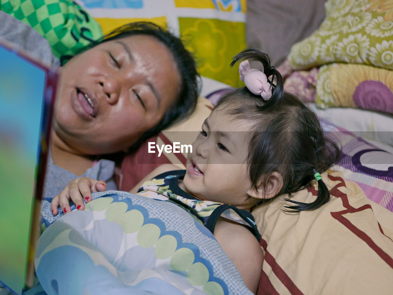 A baby girl, 2 years old, enjoys listening to her auntie reading aloud to her a bedtime story
