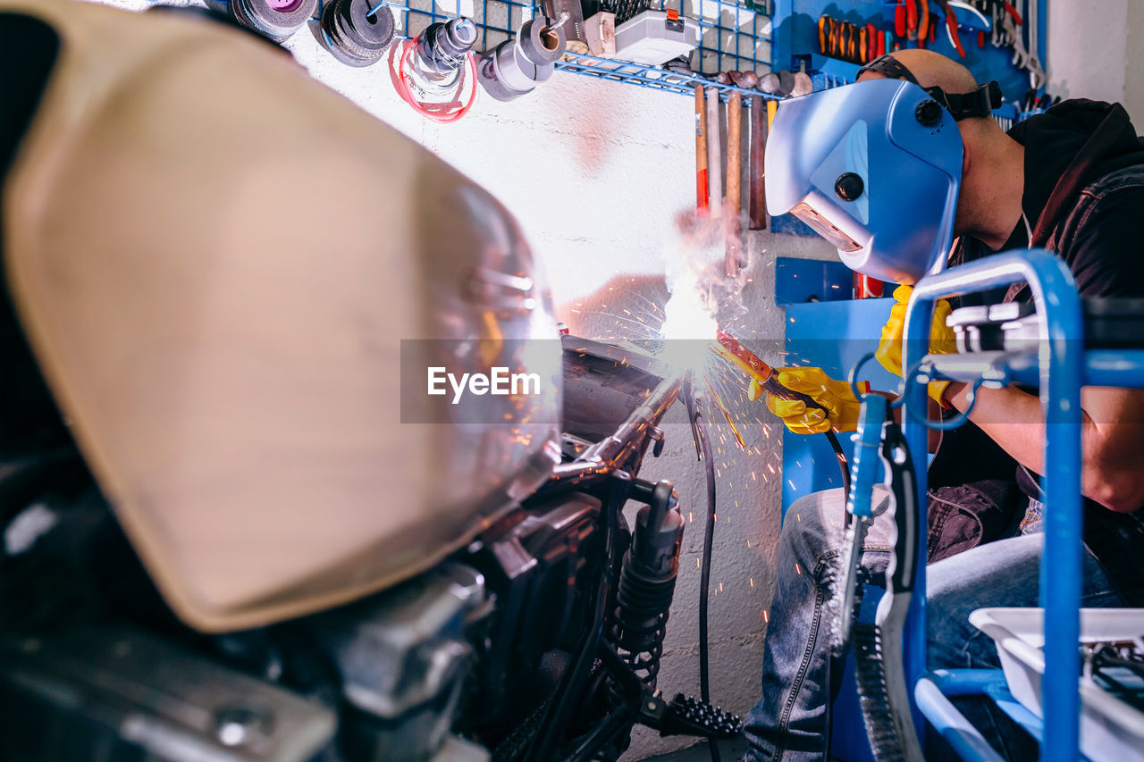 Mature mechanic repairing motorcycle in garage