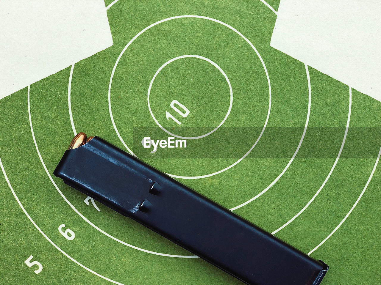 High angle view of a target practice sheet and a loaded weapon loader