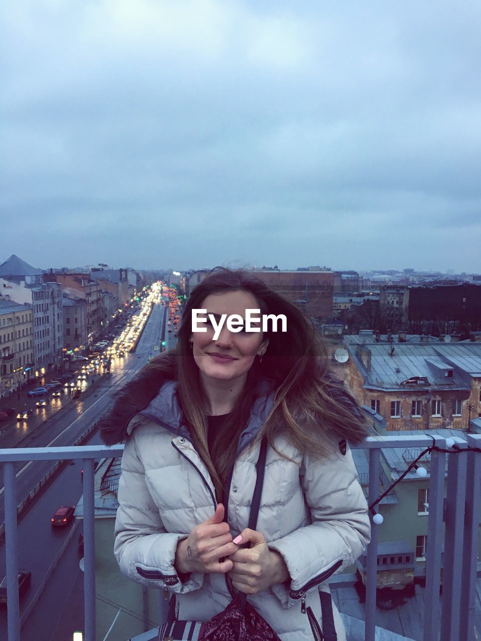 Portrait of young woman in city against sky