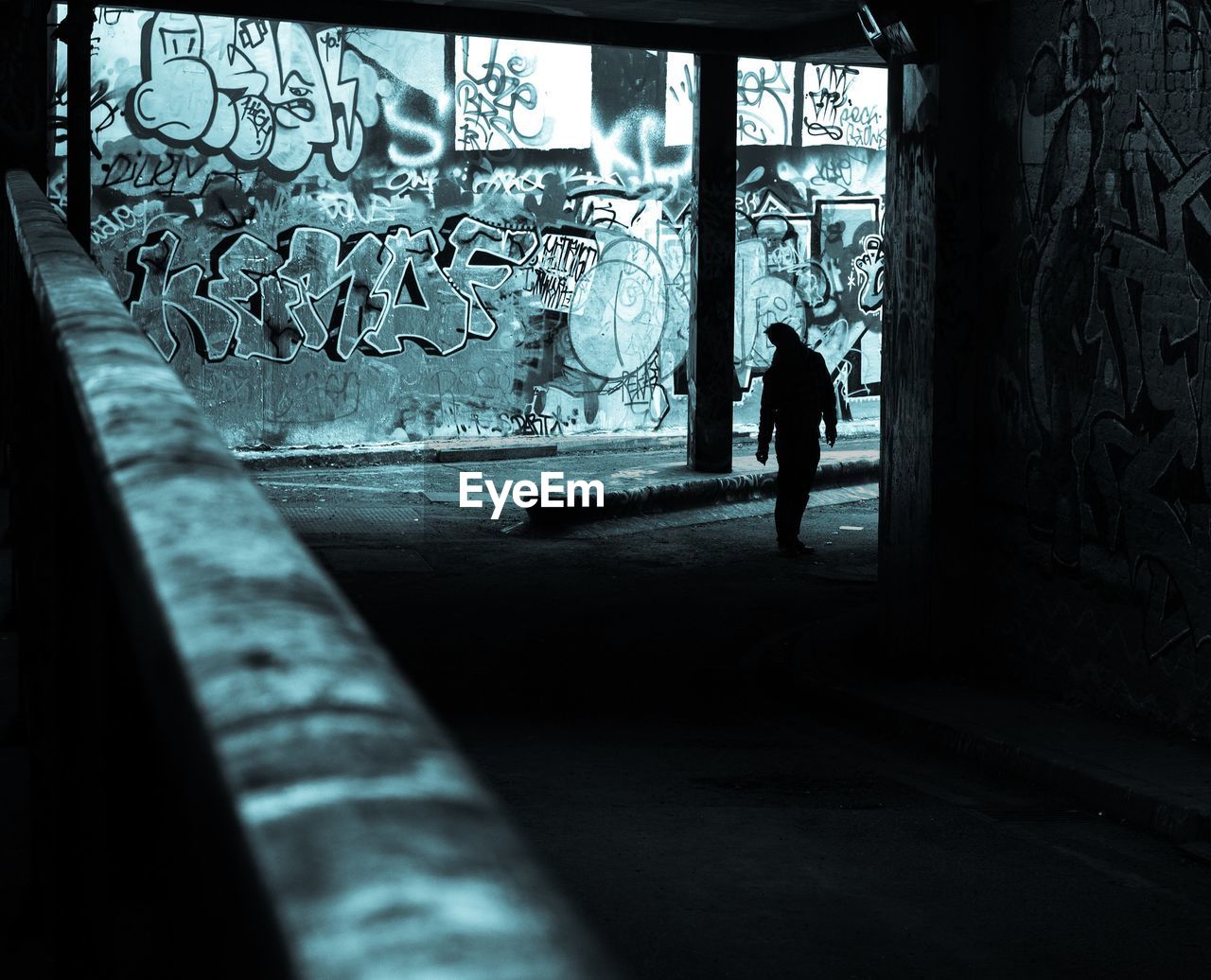 Silhouette person in graffiti tunnel