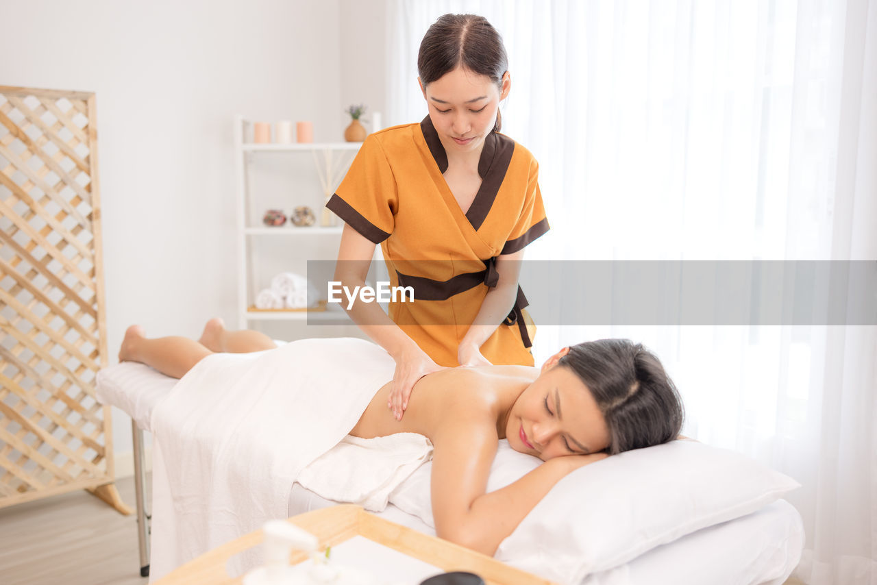 In a spa salon, a young woman enjoys massage therapy.