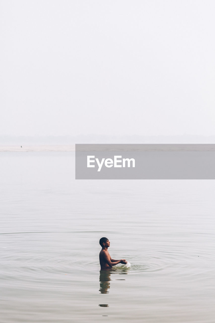 Man swimming in sea against clear sky