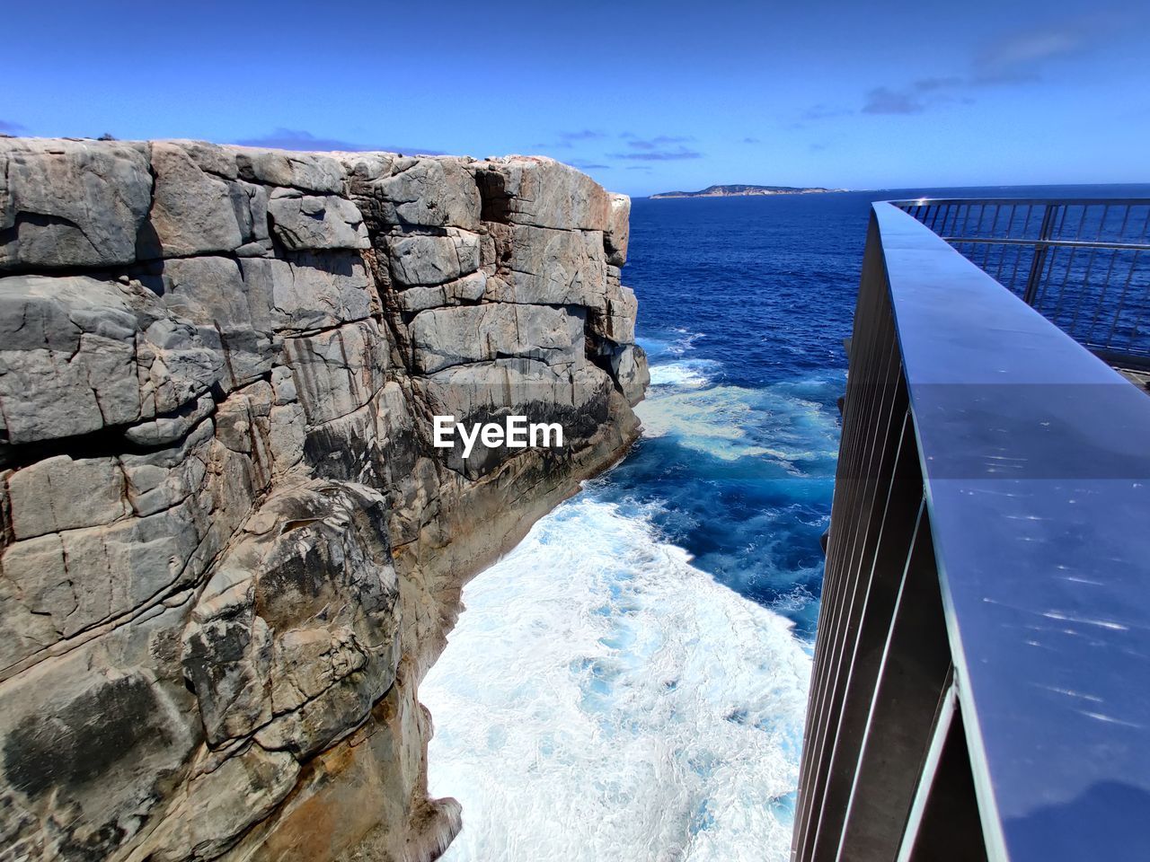 Rock formations by sea against blue sky