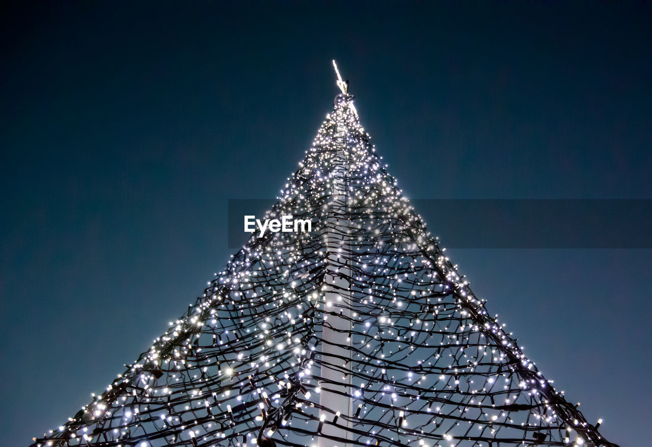 Low angle view of illuminated christmas tree against clear sky at night