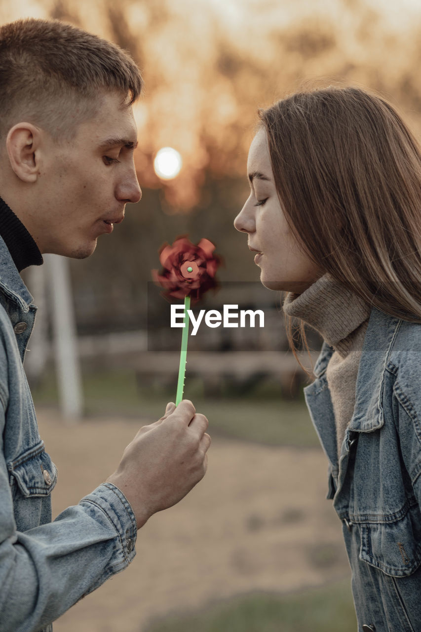 Young man and woman blowing on a wind toy, ecology concept