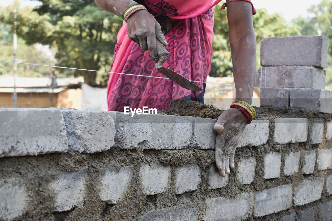 Full length of woman laying bricks on wall