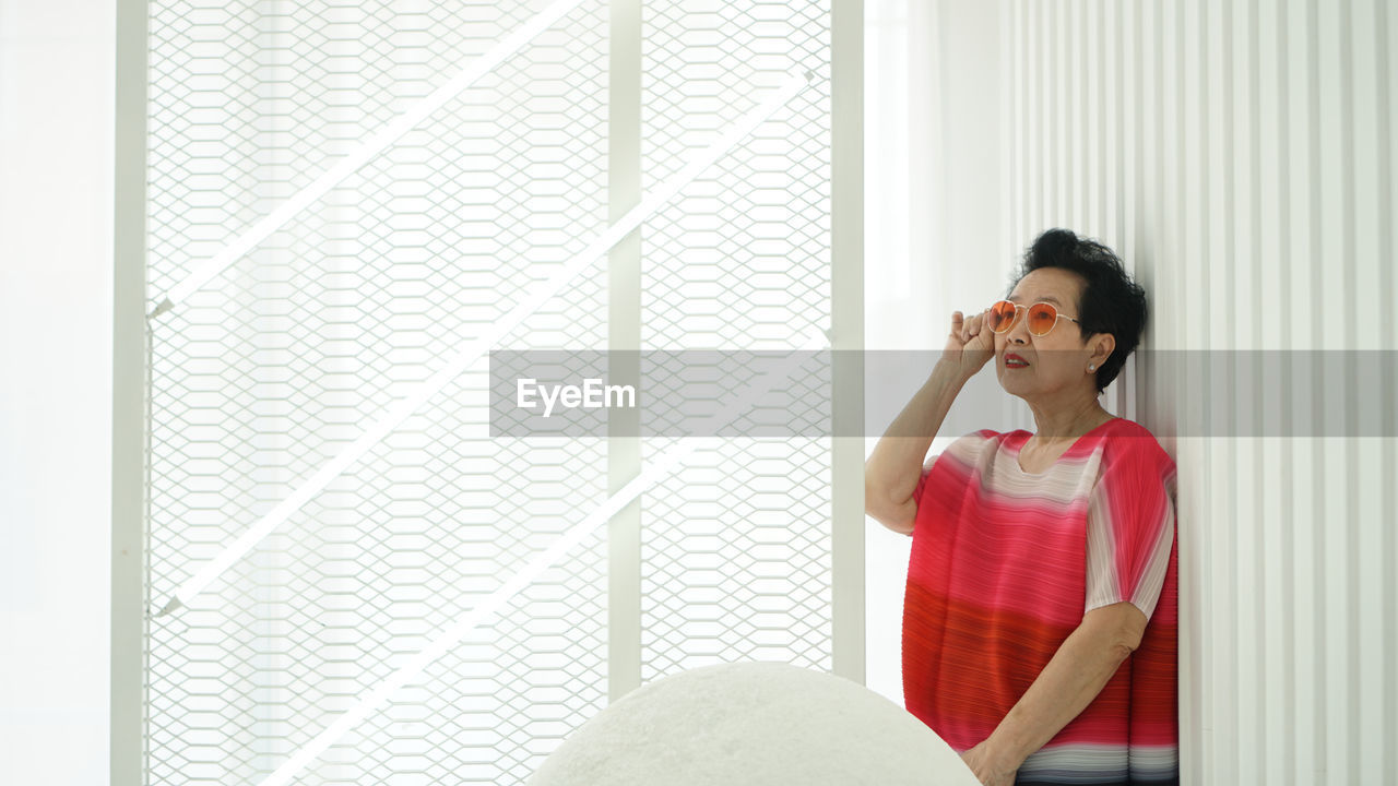 Senior woman wearing sunglasses standing at home