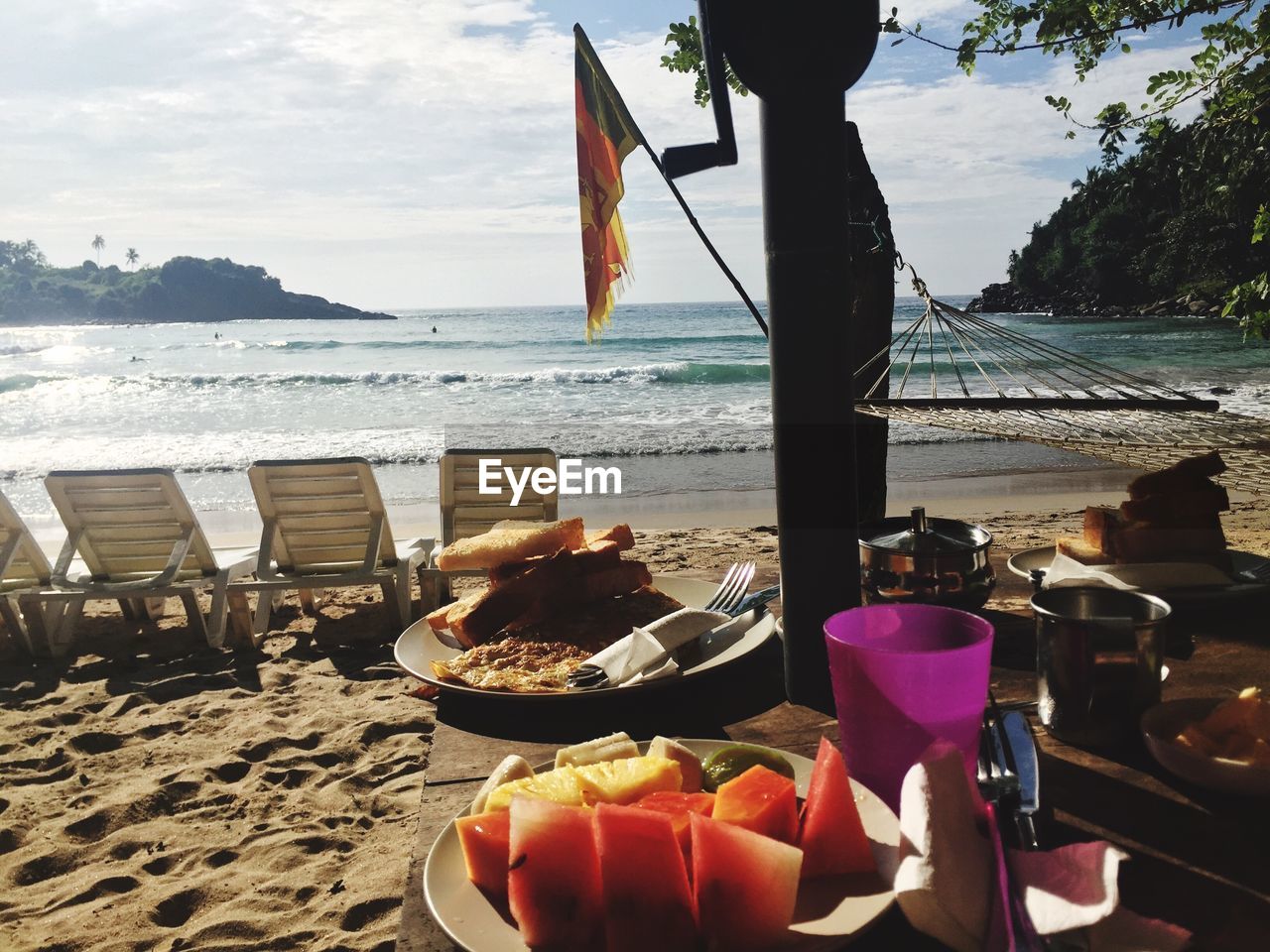 Fruits in plate on table at beach against sky