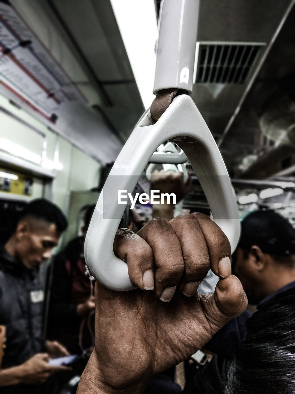 Cropped hand of man holding handle in train