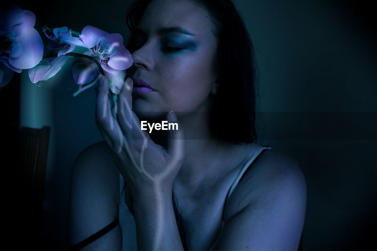 Close-up of woman smelling flower in darkroom