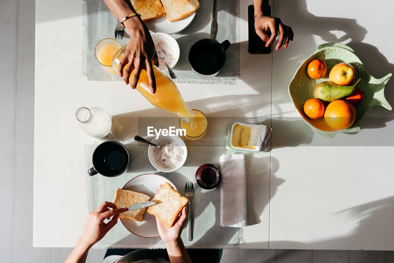 Top view of multiethnic young women eating healthy breakfast food at table in morning at home