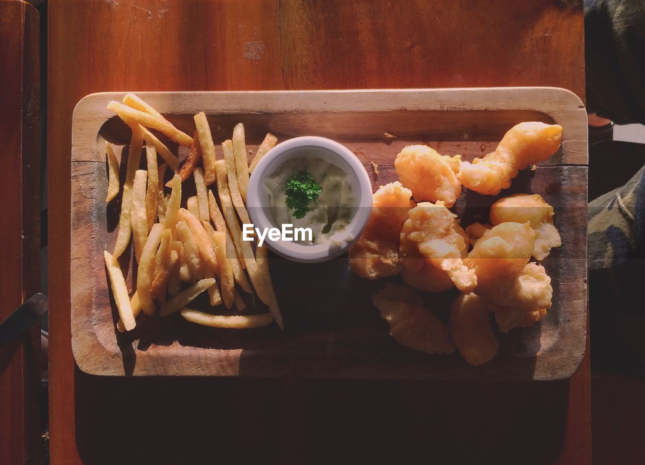 Directly above view of fresh fish and chips with mayonnaise dip in tray on table