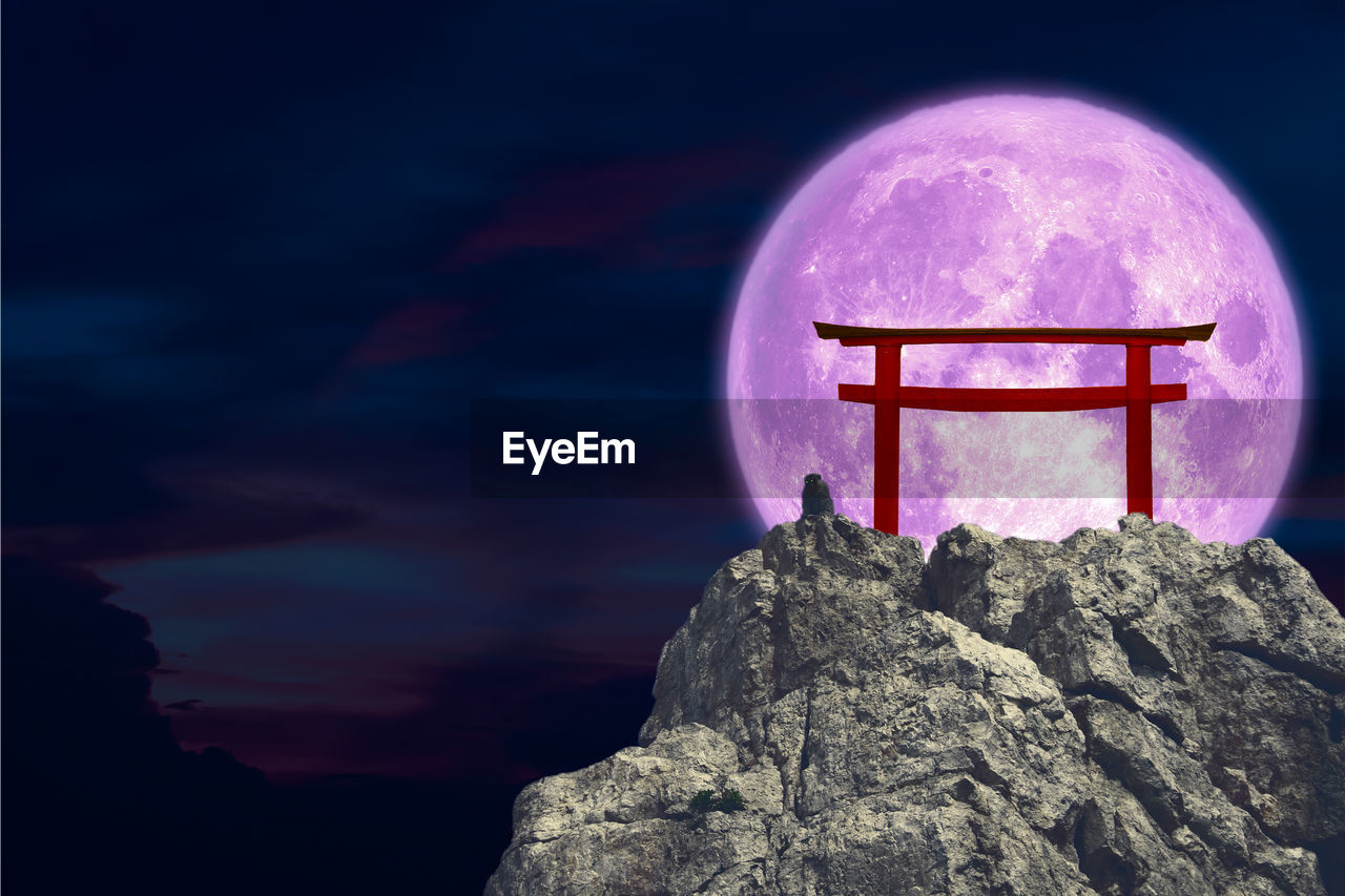 Full pink moonback torii .scenic view of rock formation against sky at night