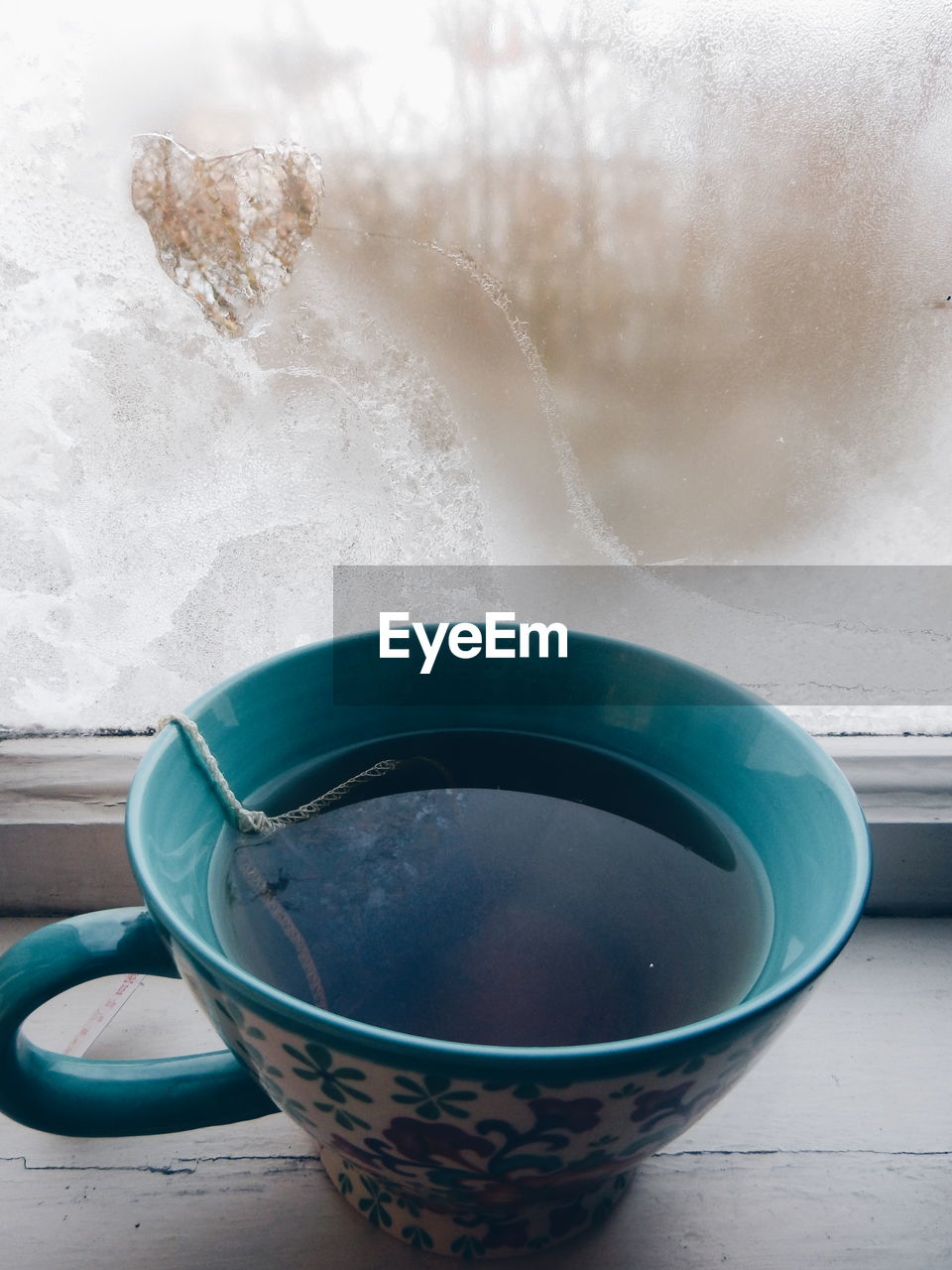 Close-up of black tea by condensed window during winter