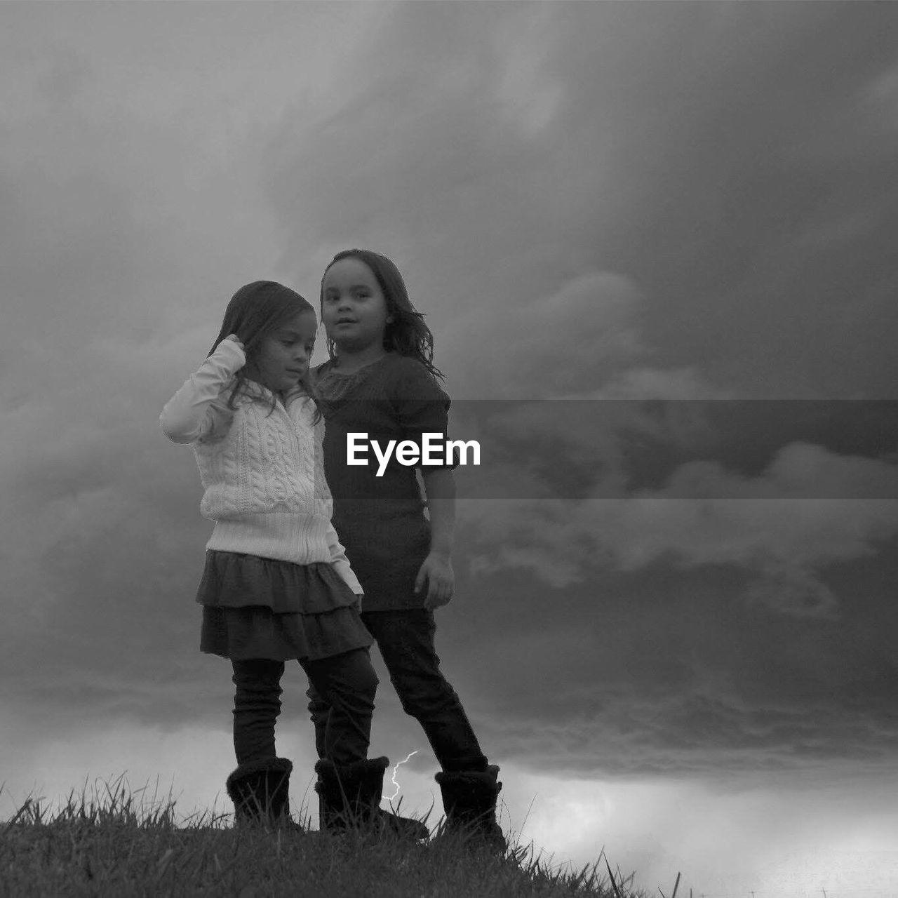 FULL LENGTH OF MOTHER AND DAUGHTER STANDING ON LANDSCAPE AGAINST SKY