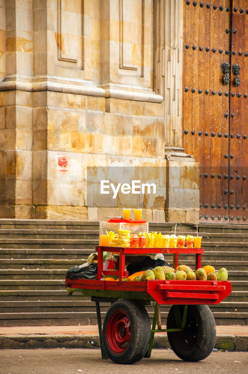 Fruits and juices for sale on cart against historic building at bolivar square