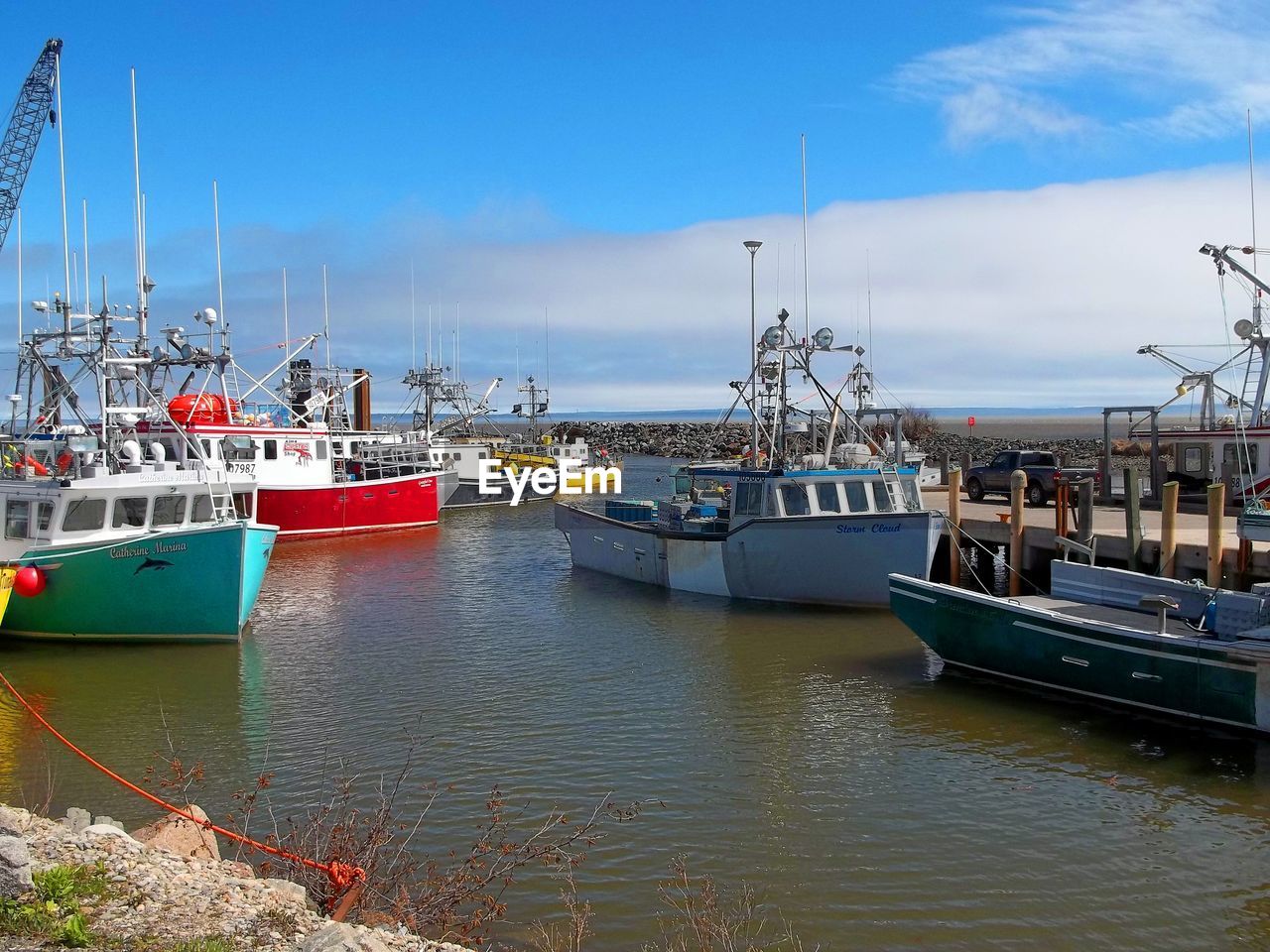 BOATS MOORED IN HARBOR AGAINST SKY