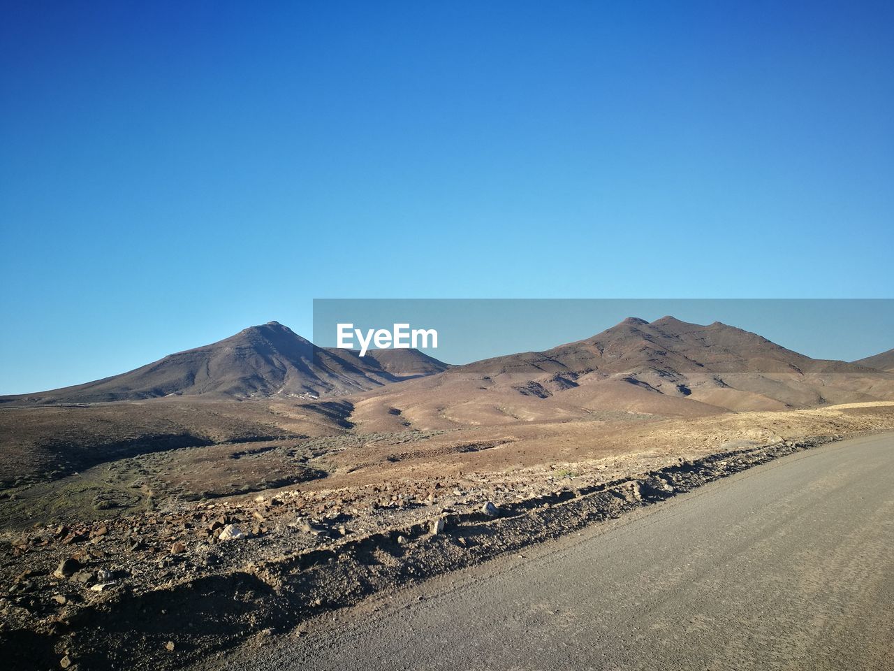 Scenic view of arid landscape against clear blue sky